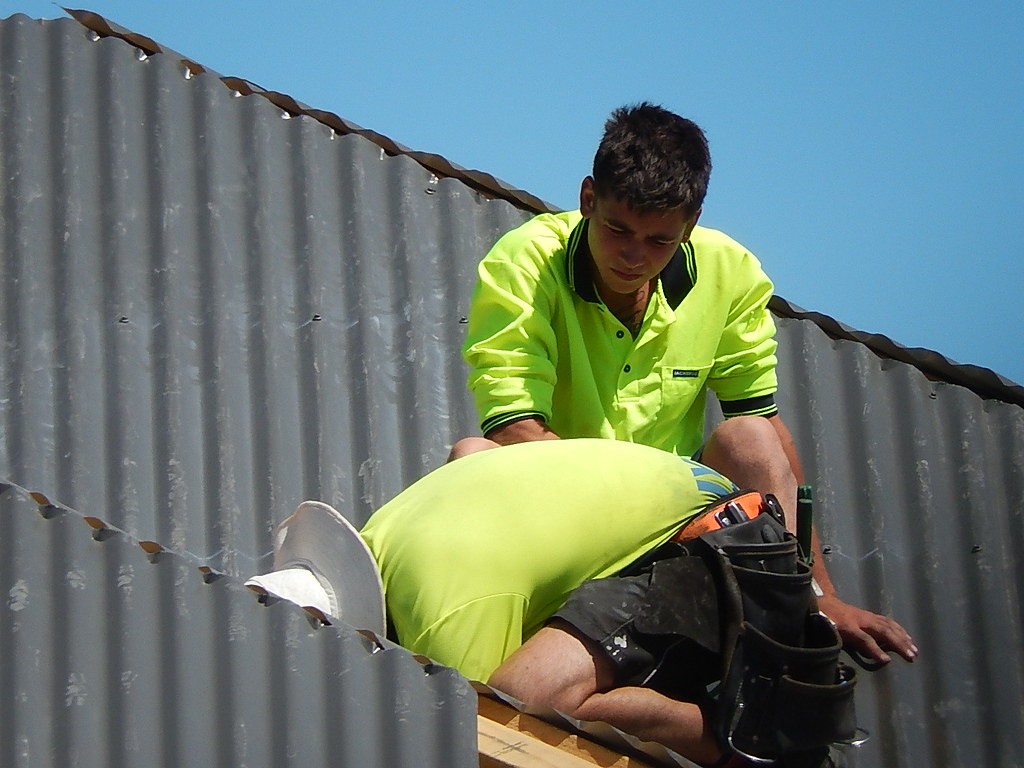 Roofer securing a corrugated metal roof